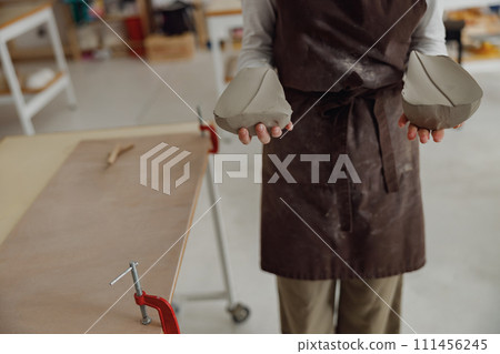 Close up of ceramist woman wearing apron is preparing clay to make pottery pieces in her studio 111456245