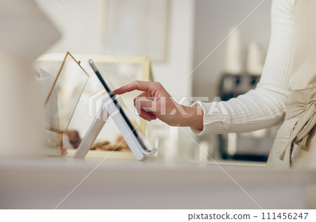 Close up of barista standing at the counter in coffee shop and takes orders from client 111456247