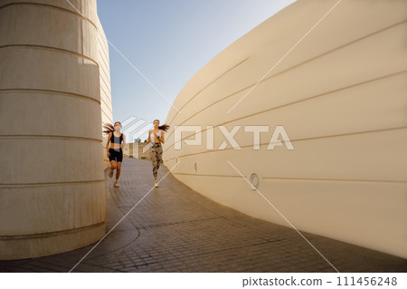 Active female friends in sportswear running outdoors on a sunny day . Morning jog 111456248