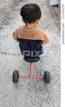 Infant riding a tricycle Infant riding a tricycle 111456257