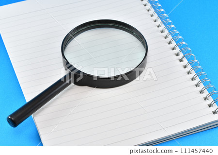 notebook and magnifying glass 111457440
