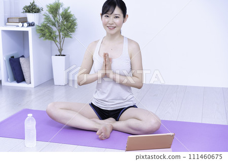 Middle-aged woman doing online yoga at home Middle-aged woman doing online yoga at home 111460675