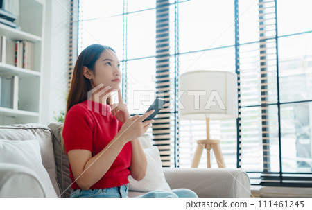 Happy young asian woman relax on comfortable couch at home texting messaging on smartphone 111461245