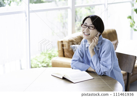 A middle-aged woman reading a book while listening to music in the living room 111461936