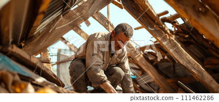 an immigrant man constructing a camp shelter using piece of materials 111462286