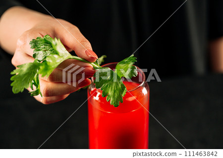 Hand making bloody mary cocktail with celery 111463842