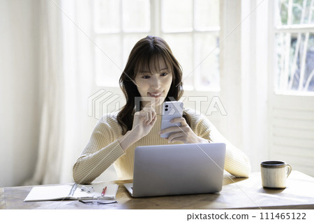 A woman using a smartphone while using a laptop A woman using a smartphone while using a laptop 111465122