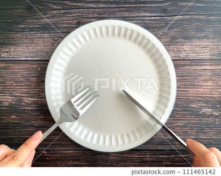 Hand with fork and knife and white plate 111465142