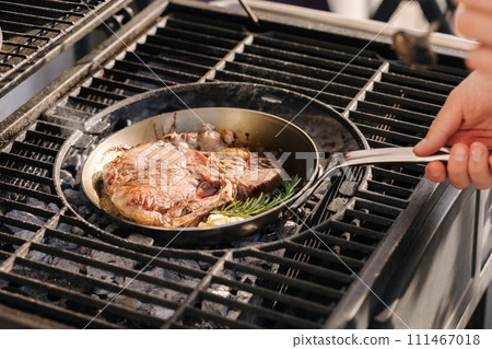 A steaming beef tenderloin steak is grilled in a grill pan. The concept of the recipe, T-bone steak. Hot coals 111467018