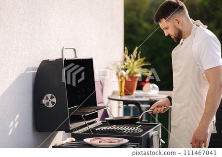 Middle selection of man in apron using wooden spoon to mix vegetables on frying pan. Prepare food on grill Middle selection of man in apron using wooden spoon to mix vegetables on frying pan. Prepare food on grill 111467041