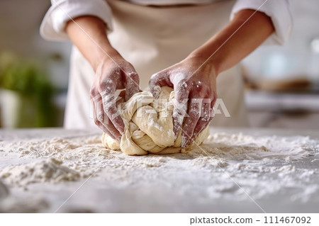 Close up view of pair of hands kneading dough in the kitchen on white table Close up view of pair of hands kneading dough in the kitchen on white table 111467092