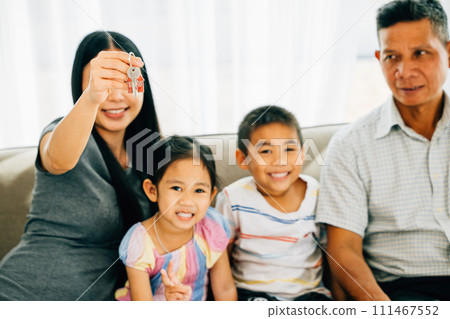 A joyful family mother holding new house keys poses for a portrait with children and dad. Reflecting excitement happiness and the pride of real estate ownership in a heartwarming scene. A joyful family mother holding new house keys poses for a portrait with children and dad. Reflecting excitement happiness and the pride of real estate ownership in a heartwarming scene. 111467552