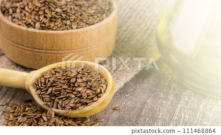 Brown flax seeds and flaxseed oil on the wooden table on sunlight Brown flax seeds and flaxseed oil on the wooden table on sunlight 111468864