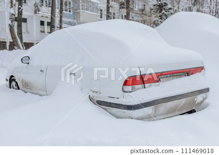 Parking of cars covered with snow. Heavy snowfall covered the road. Car in the snow.Consequences of a snowstorm.Abandoned car on the side of the road Parking of cars covered with snow. Heavy snowfall covered the road. Car in the snow.Consequences of a snowstorm.Abandoned car on the side of the road 111469018
