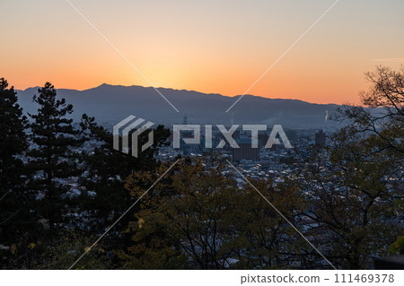 從日本福島縣會津若松市飯盛山看到的魔法時刻的城市景觀和日落天空 從日本福島縣會津若松市飯盛山看到的魔法時刻的城市景觀和日落天空 111469378