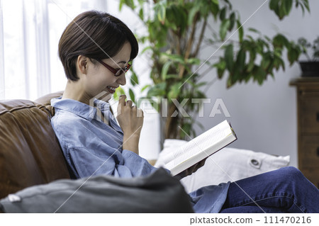 Middle-aged woman reading on the sofa 111470216