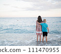 A happy boy and girl in shorts enjoying the beach scenery with water and sky 111470955