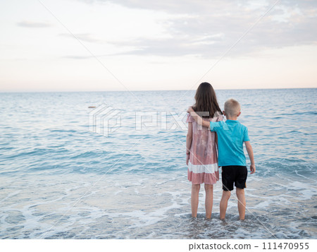 A happy boy and girl in shorts enjoying the beach scenery with water and sky 111470955