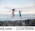 A boy and a girl are jumping into the ocean 111470956