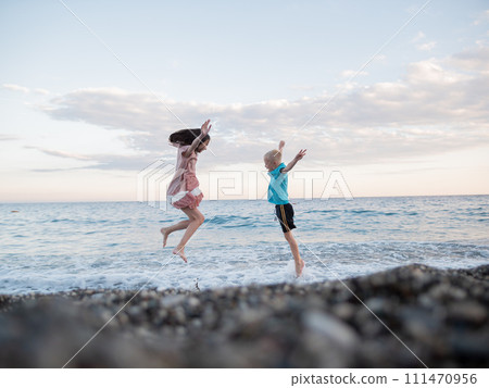 A boy and a girl are jumping into the ocean 111470956