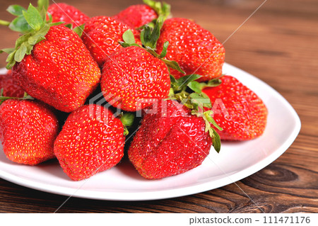 red large strawberries in a white plate on a natural brown background red large strawberries in a white plate on a natural brown background 111471176