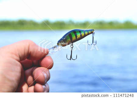 fishing wobbler in hand on a river background close-up fishing wobbler in hand on a river background close-up 111471248