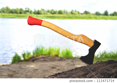 a beautiful-shaped ax sticks out in a tree, with a yellow handle close-up, on a natural background a beautiful-shaped ax sticks out in a tree, with a yellow handle close-up, on a natural background 111471714