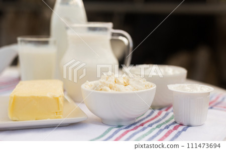 Milk, cottage cheese, cream, cheese on table against background of cows 111473694