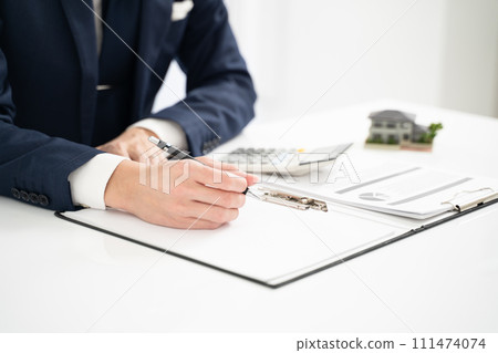Hands of a businessman assessing real estate prices Hands of a businessman assessing real estate prices 111474074