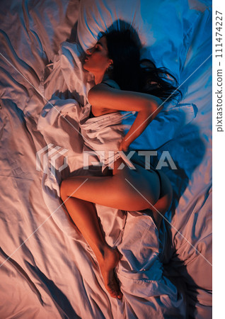 slender beautiful girl with a sexy body and ass in panties erotically lies on the bed under blanket in the bedroom. View from above top slender beautiful girl with a sexy body and ass in panties erotically lies on the bed under blanket in the bedroom. View from above top 111474227