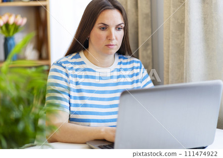 Focused Woman Working on Laptop in a Home Setting Focused Woman Working on Laptop in a Home Setting 111474922