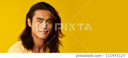 Elegant handsome smiling young Asian man with long hair, on yellow, banner, copy space, portrait. 111475123