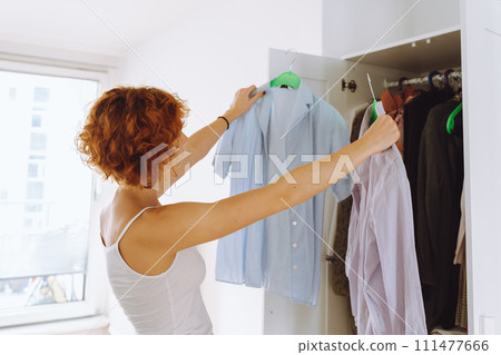 Teenager girl looking at clothes in wardrobe 111477666