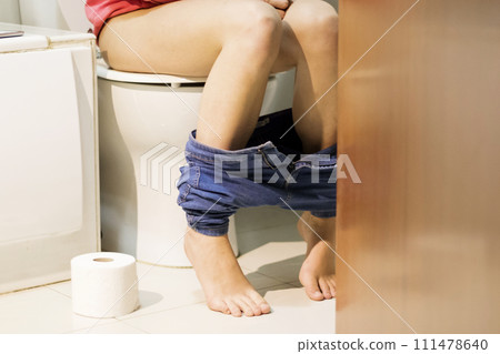 Cropped image of woman shitting in the toilet consulting the mobile phone 111478640