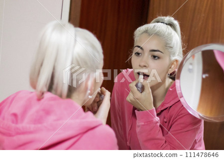 Beautiful young woman making make-up near mirror at home. 111478646