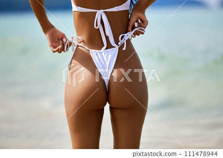 Sexy model's ass in white bikini on the blue water background Sexy model's ass in white bikini on the blue water background 111478944