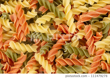 Raw colored pasta fusilli. Uncooked pastas background. Raw colored pasta fusilli. Uncooked pastas background. 111479278