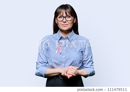 Middle-aged woman with pink ribbon symbolizing International Breast Cancer Day 111479511