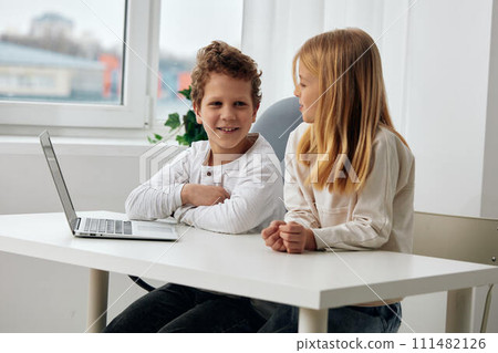 Happy siblings studying at home using laptops for online learning 111482126