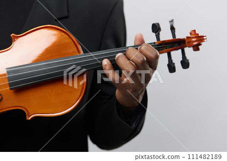 Closeup of a man in a black suit playing a violin on a white background, musical performance concept 111482189