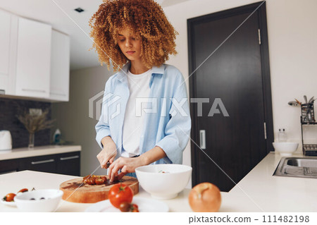 Beautiful young African American woman cooking healthy food in modern kitchen at home 111482198