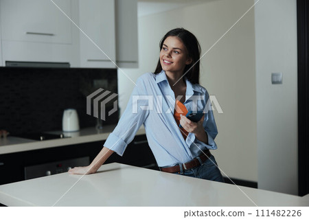 Woman standing in kitchen holding wine glass and looking at camera, lifestyle concept 111482226