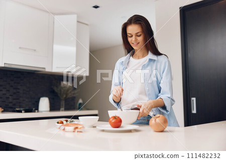 Attractive woman cooking healthy food in modern kitchen, lifestyle concept for advertising photography Attractive woman cooking healthy food in modern kitchen, lifestyle concept for advertising photography 111482232