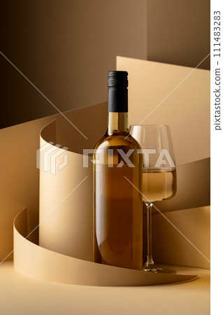 Bottle and glass of white wine on a beige background. 111483283