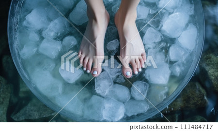 Close-up of bare feet submerged in a basin full of ice cubes and water, relief or treatment from cold therapy 111484717