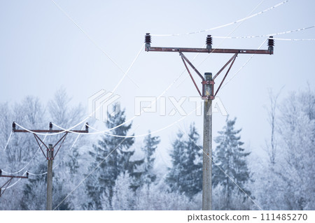 Retro electric pole with frozen wires and forest on background 111485270