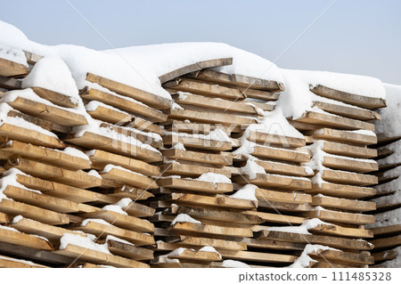 Wooden boards pile covered with snow - construction wood winter background 111485328