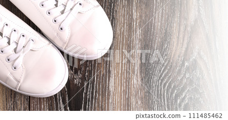 White sneakers on dark wooden surface. Shoes for women in sport fashion style 111485462