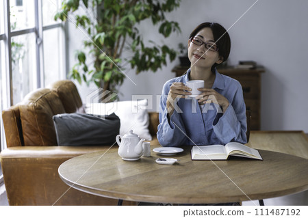 Middle-aged woman reading while drinking tea in the living room 111487192