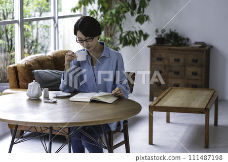 中年婦女在客廳喝茶看書 111487198